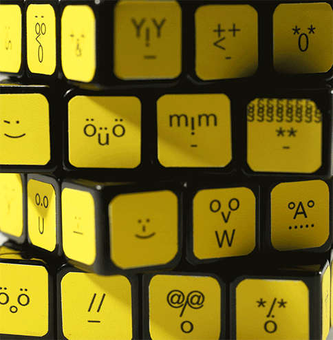 An animation of a yellow Rubik's cube. The small cubes are collaged with smileys. Each cube has a different smiley. When the cube is in motion the smileys change their expressions.